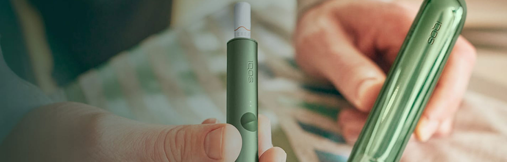 A moss green IQOS ILUMA Holder and Pocket Charger.